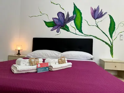 a purple bed with towels and flowers painted on the wall at Trastevere Marconi Apartment in Rome