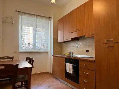 a kitchen with wooden cabinets and a table and a window at Trastevere Marconi Apartment in Rome
