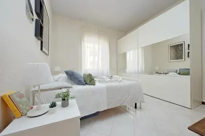 a white bedroom with a bed and a living room at Giant Cola di Rienzo Apartment in Rome