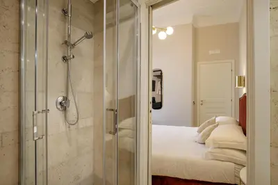 a bathroom with a glass shower with a bed at Daplace - Santa Susanna Suites in Rome