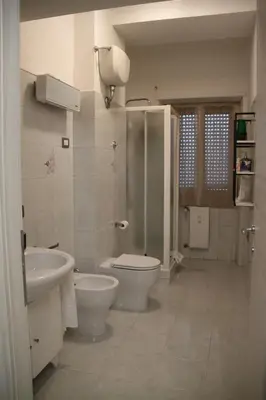 a white bathroom with a toilet and a sink at Appartamento Hector in Rome