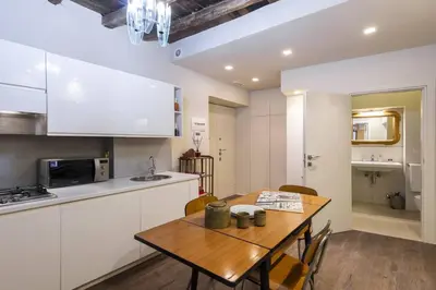 a kitchen with a wooden table and a kitchen with white cabinets at Luxury Fori Imperiali Apartment in Rome