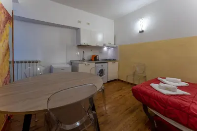 a room with a table and a red couch and a kitchen at Pellegrino Apartments in Rome