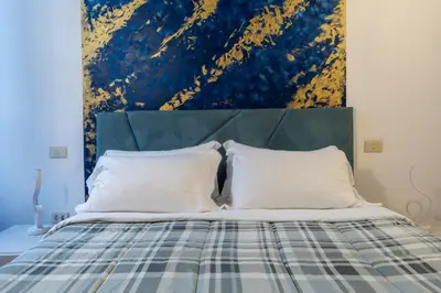 a bed with a blue and yellow painting above it at Pellegrino Apartments in Rome
