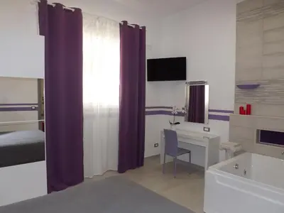 a bedroom with purple curtains and a bed and a desk at Apartment Nido di Roma Suite, Jacuzzi King Size, Metro C in Rome