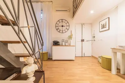 a living room with a staircase and a clock on the wall at Campo De' Fiori 35 (Centro di Roma/Appartamento accogliente) - FromhometoRome in Rome