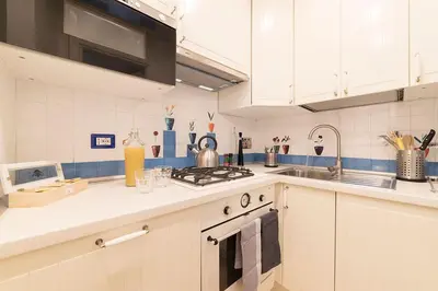 a kitchen with white cabinets and a stove top oven at Campo De' Fiori 35 (Centro di Roma/Appartamento accogliente) - FromhometoRome in Rome