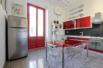 a kitchen with a red table and a refrigerator at Tibullo ,Classico ed Elegante Appartamento in Rome