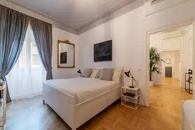 a white bedroom with a white bed and a mirror at Toscana 6 - FromhometoRome in Rome