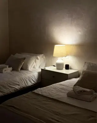 a bedroom with two beds and a lamp on a night stand at Ten Miles Guesthouse Roma in Rome