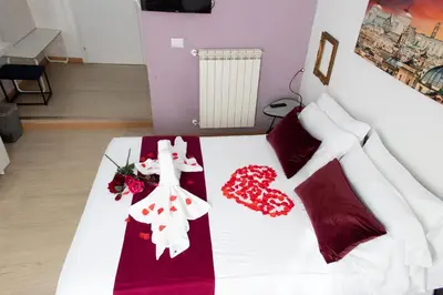 a bedroom with a bed with red and white sheets and flowers at ArtHouse Termini in Rome