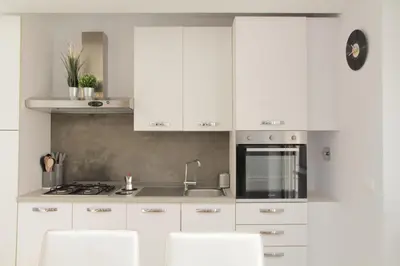 a white kitchen with white cabinets and white chairs at YCH-Stylish 3 bedrooms apartment near Vatican in Rome