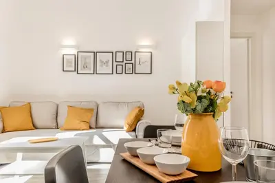 a living room with a table and a yellow vase with flowers at Elena's house in Rome