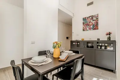 a dining room with a table and chairs and a kitchen at Elena's house in Rome