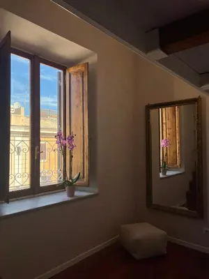 a room with a window with a mirror and flowers at Penthouse 23 - Vatican Charming Apartment in Rome