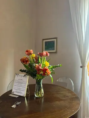 a vase of flowers on a table with a sign at Penthouse 23 - Vatican Charming Apartment in Rome