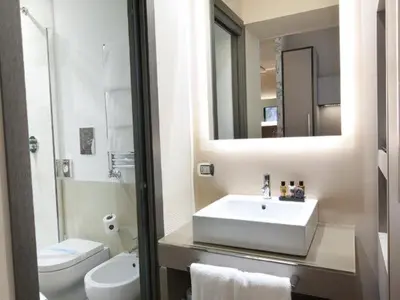 a bathroom with a sink and a toilet and a mirror at Trevi Palace Hotel in Rome