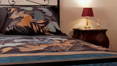 a bed with a colorful blanket with a lamp on a table at Italian romance - A fine apartment in Rome in Rome