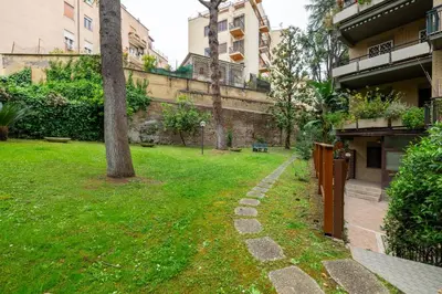 a grassy yard with a tree next to a building at Vatican home garden by Varental in Rome