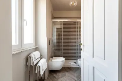 a white bathroom with a toilet and a window at Vatican Stunning 2 BR Apartment in Rome