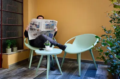 a person sitting in a chair reading a newspaper at Mamaco Roma in Rome