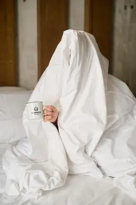 a person laying in bed under a blanket holding a coffee cup at Mamaco Roma in Rome