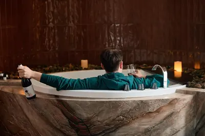 a man sitting in a bath tub with a bottle of wine at Mamaco Roma in Rome