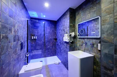 a blue tiled bathroom with a toilet and a shower at Mamaco Roma in Rome