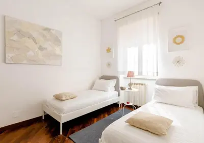 a white room with two beds and a window at Romely House St Peter Apartment in Rome