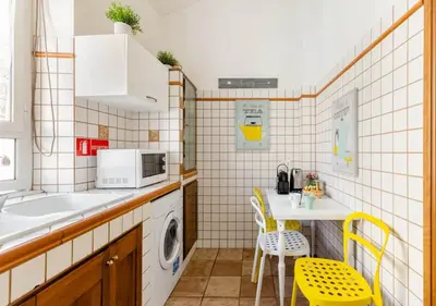 a kitchen with a sink and a table with yellow chairs at Romely House St Peter Apartment in Rome