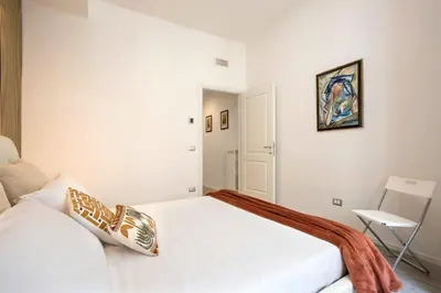 a white bedroom with a bed and a chair at Domus White in Rome