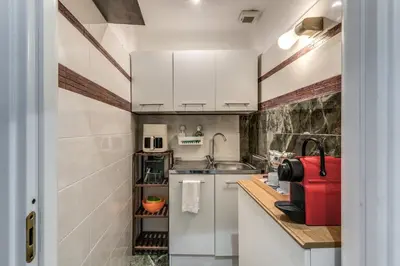 a small kitchen with white cabinets and a red suitcase at Spanish Step Dream Suites in Rome