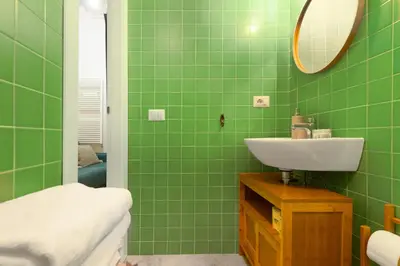 a green bathroom with a sink and a mirror at Cozy Suite Saint John in Rome