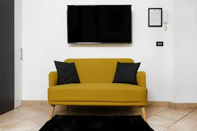 a yellow couch in a living room with a tv at Dea Clodia studio flat in Rome