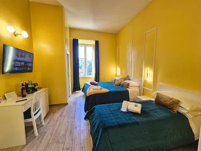 a hotel room with two beds and a desk at Residenze Serventi Longhi in Rome