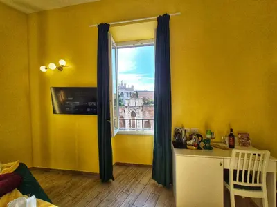 a yellow room with a window and a table and a chair at Residenze Serventi Longhi in Rome