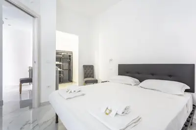 a white bedroom with a large white bed with two towels at Portside Aparthotel in Rome