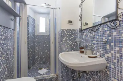 a blue tiled bathroom with a sink and a shower at Sweet House Campo de’ Fiori in Rome