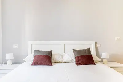 a white bed with two red pillows on it at [Flaminio * * * * *] - Loft con Giardino in Rome