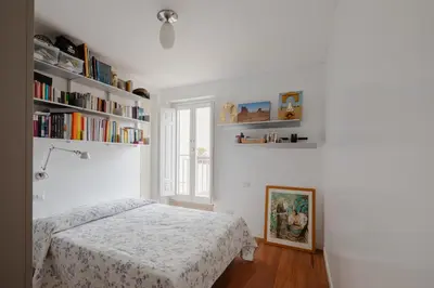 a white bedroom with a bed and bookshelves at Cesarina Home in Rome