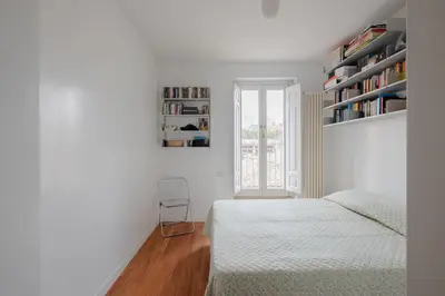 a white bedroom with a bed and a book shelf at Cesarina Home in Rome