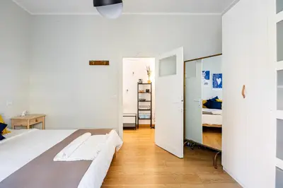 a white bedroom with a bed and a mirror at Donna Olimpia tra Gianicolo e Trastevere in Rome