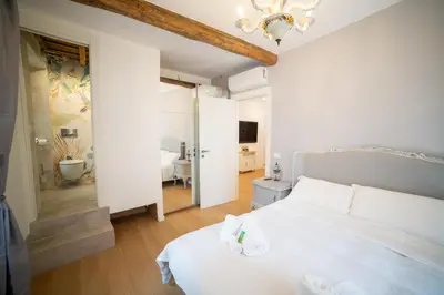 a white bedroom with a white bed and a bathroom at In the shadow of the Colosseum in Rome