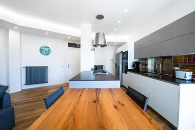 a living room with a wooden floor and a kitchen at Casa del Marchese del Grillo in Rome