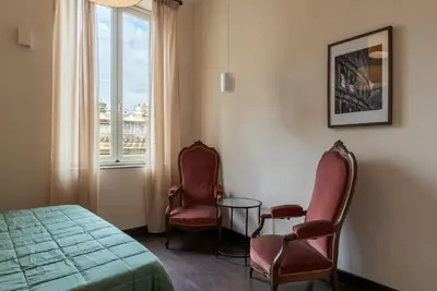 a room with two chairs and a bed and a window at GuestHost - Colosseo & San Clemente Apartment in Rome