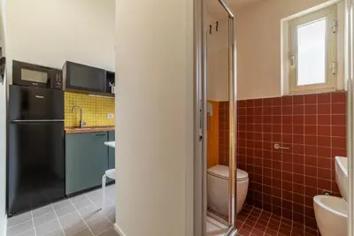 a bathroom with a toilet and a sink and a refrigerator at GuestHost - Colosseo & San Clemente Apartment in Rome
