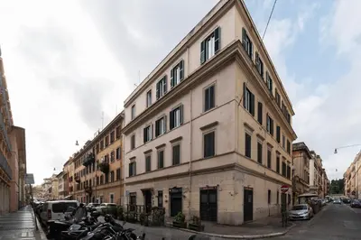 a large white building on the corner of a street at GuestHost - Colosseo & San Clemente Apartment in Rome