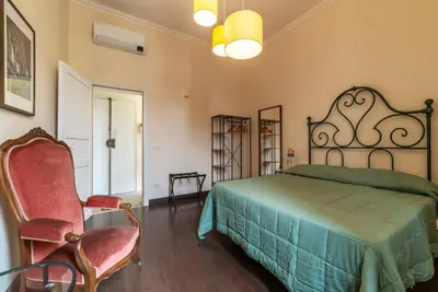 a bedroom with a bed and a chair at GuestHost - Colosseo & San Clemente Apartment in Rome