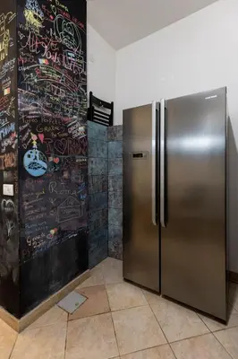 a stainless steel refrigerator in a room with graffiti at Domus Christina in Rome