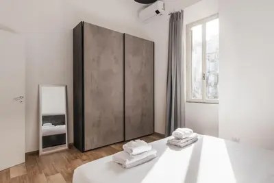 a white room with a bed and a mirror at WMR Apartment near Vatican in Rome